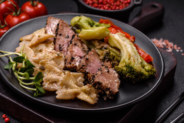 Bowl with slices of baked tuna with broccoli, tomatoes and fusili pasta