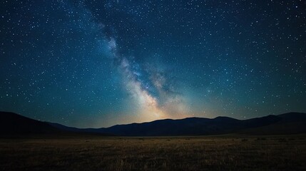 Sticker -   A stunning image of a starry night sky, illuminated by the glowing Milky Way galaxy above a field of green grass and majestic mountain ranges in the background