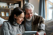 © Анастасия Гайкова - Family values concept, senior man and adult woman sitting together,  looking at a tablet screen