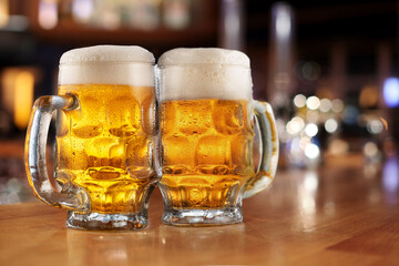 Two glasses of beer whis beer foam and water drops on the bar counter in the pub.