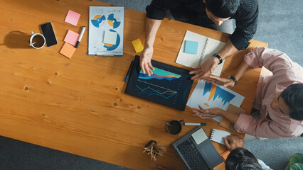 Wall Mural - Executive manager explain financial graph to colleague at meeting room. Top aerial view of diverse marketing team sharing idea and planning strategy while sitting at table with tablet. Convocation.