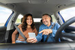 © Home-stock - Happy spouses having car trip together, using mobile application on cellphone, sitting on front seats, view from vehicle dashboard