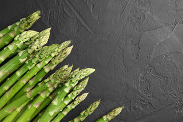 Sticker - Fresh green asparagus stems on gray textured table, top view. Space for text