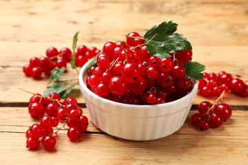 Sticker - Fresh red currants and green leaves on wooden table, closeup