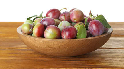 Wall Mural - Fresh plums and green leaves in bowl on wooden table against white background