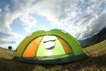 Wall Mural - Tent on green grass in mountains, low angle view. Fisheye lens effect