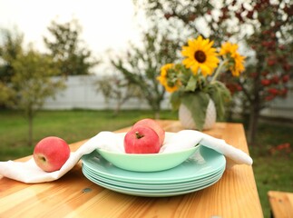 Sticker - Apples and vase with sunflowers on wooden table in garden, selective focus