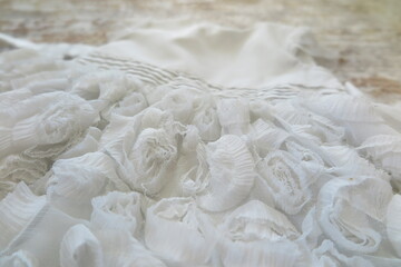 close up of a white knitted fabric, detail of a marble, fabric flowers, lace