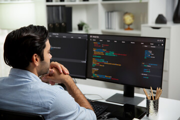 Concentrating in smart IT developer working software development coding on two pc screen, creating virus firmware application program for latest update version on website at modern office. Surmise.