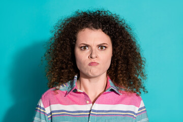 Wall Mural - Photo portrait of young curly haired dissatisfied and gloomy girl wearing polo t shirt isolated on aquamarine color background