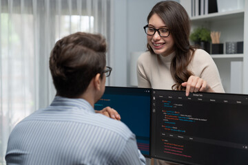 Wall Mural - woman colleague standing opposite to man programmer working on desk to discuss coding website softwa