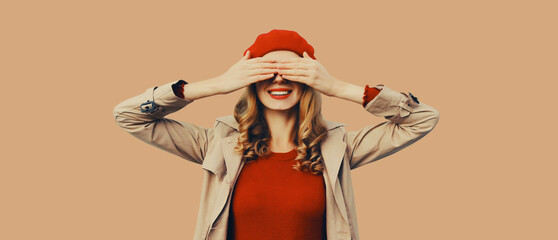 Poster - Stylish surprised young woman covering her eyes with hands, fashionable girl in red hat, jacket