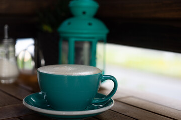 turquoise mug with coffee on a wooden table in a cafe in the background a turquoise lantern