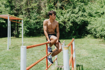 Wall Mural - Fit and strong male sports person working out in the park doing outdoor exercises on a sunny day.