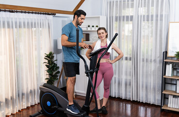 Wall Mural - Athletic and sporty young couple or fitness buddy running on running machine together, home body workout exercise session as healthy sport lifestyle at home. Gaiety home exercise workout training.