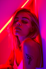 Poster - A woman with a tattoo on her arm is sitting in a room with neon lights