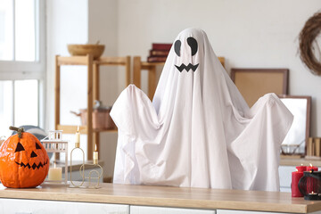 Sticker - Person in Halloween costume of ghost with carved pumpkin and burning candles at home