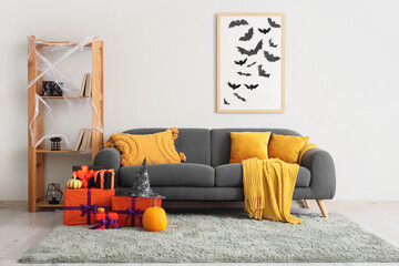 Interior of festive living room with grey sofa, Halloween decorations and gift boxes