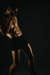 © qunica.com - Fit man displaying his toned abs in a dark studio setting, emphasizing fitness, strength, and a muscular physique.