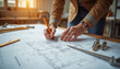 © abu - An engineer’s hands sketch blueprints on a drafting board, surrounded by technical tools and detailed plans, highlighting expertise in a professional workspace.