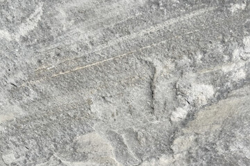 Gray Rock Formation with Marble Texture. Close-up view of a gray textured rock formation. The surface is uneven and contains a variety of patterns such as grooves, ridges, and small depressions. 