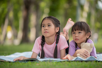 Happy Asian family children elder sister and younger sister reading a book together