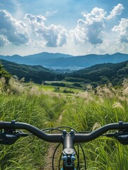 Wall Mural - Mountain landscape from cyclist perspective. Peaceful countryside with rolling hills and green grass. Majestic mountains rise in distance. Perfect scenery for travel agency and tours.