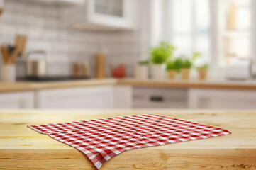 Poster - Empty wooden table with red checkered tablecloth in front of blurred kitchen background, product display montage. High quality photo