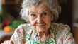 © K-MookPan - Cheerful elderly woman in a floral apron, enjoying a moment in her kitchen, surrounded by fresh ingredients and warm light.