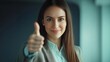 © K-MookPan - A confident woman giving a thumbs up, expressing positivity and approval in a professional setting.