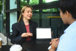 © Prathankarnpap - Young businesswoman presenting something on digital tablet to her colleague or client, sitting at outdoor cafe