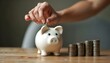 © Kh - A hand depositing a coin into a piggy bank