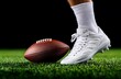 © Emqan - Close-up of football player's leg in striped socks on grass holding an American football