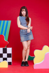 Wall Mural - Fashionable photo concept stylish portrait young confident woman model Asian beautiful female wearing trendy denim sleeveless short top and jeans mini skirt, posing in studio on a colorful background.