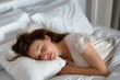 © Vadym - Young woman sleeps peacefully on white pillow in cozy bed. Soft, cotton bedding, calm atmosphere create comfortable resting place. Female lies on bed with peaceful expression, surrounded by domestic