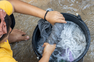 The girl washes the head of the mop in a bucket with detergent