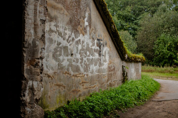 An old, moss-covered stone wall in a countryside setting signifying decay and the passage of time