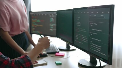 Slow motion back end software developer engineer for computer programming working together on debugging writing computing code, solving complex algorithms display on monitor in office. Burgeoning