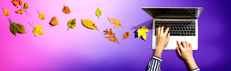 Autumn leaves with person using a laptop computer from above