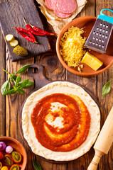 Canvas Print - Raw pizza dough with tomato sauce and basil leaves.