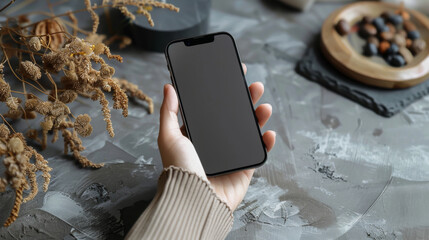 Wall Mural - Close-up of a modern smartphone in hands on a gray plaid background. Black technology phone indoors. Concept of technology, modernity.