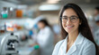 © Niks Ads - Beautiful young indian woman scientist wearing white coat and glasses in modern Medical Science Laboratory with Team of Specialists on background.