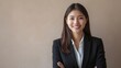© Snowstudio - Portrait of smiling attractive asian business woman wearing black suit on light beige background