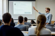 © SejutaCahaya - A young male professor gives a presentation to a class of students. He stands at the front of the classroom with his hand raised, gesturing towards a projection screen, while the students sit at desks