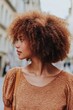 © stopcontrol - A woman with natural curly hair, wearing a bold dress and walking confidently in a city street