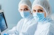 © Kunalai - Two healthcare professionals wearing masks and protective gear, focused on tasks in a modern medical environment.