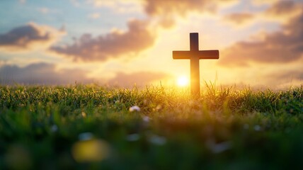 the cross on green grass with sunset in the sky background