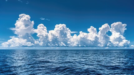 Bright blue morning sky with white clouds and deep indigo ocean in daylight creates a serene backdrop.