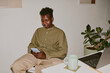 © AnnaStills - Black man chatting in social network while having break in cozy office