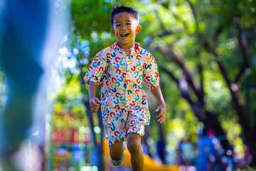 Kindergarten boy enjoy running on green grass in city playground park